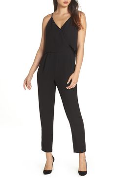A woman wearing a black jumpsuit and heels, posing with her shoulder rolled back