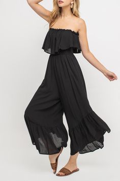 A woman wearing a black jumpsuit and sandals at a Quinceanera event.