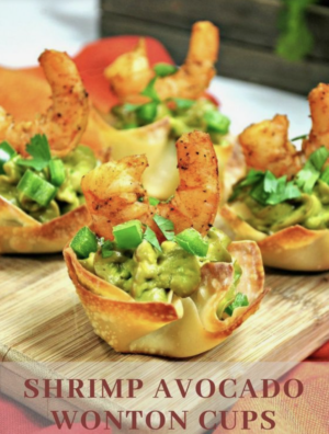 A beautifully arranged Quinceanera appetizer consisting of Caesar salad, shrimp, and avocado wonton cups displayed on a cutting board.