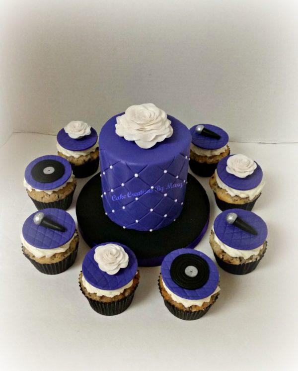 A blue Quinceanera cake surrounded by cupcakes on a table