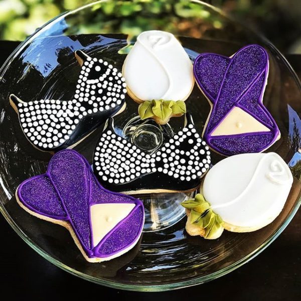 A beautiful lilac Quinceanera cake displayed on a table, along with a plate of decorated cookies