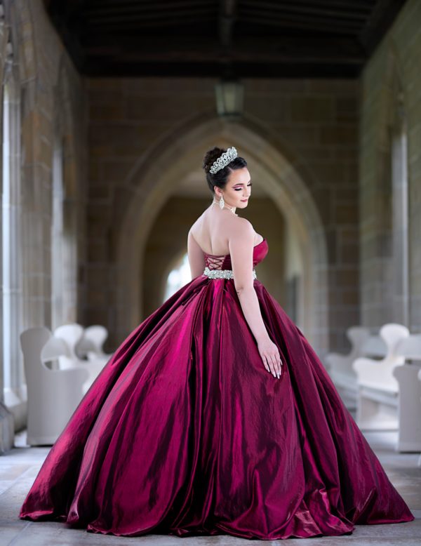 Selena, a woman in a red dress, posing for a picture in the Quinceanera chapel of our lady on the bridge