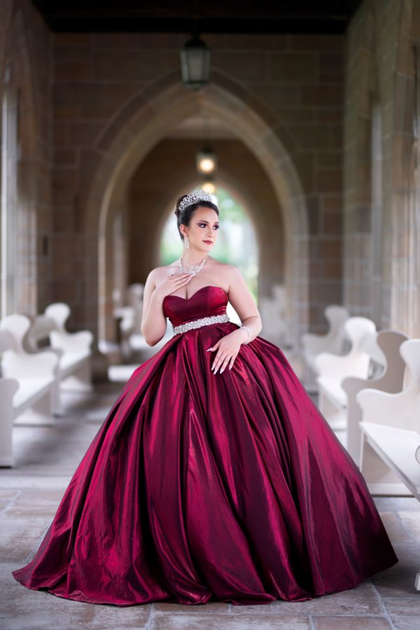 Selena, a woman in a red dress posing for a picture, in a Selena themed Quinceanera celebration.