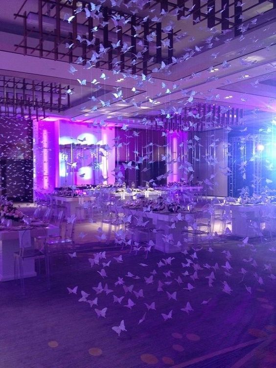 A Quinceanera celebration in a function hall party. The room is filled with lots of tables covered in paper butterflies.