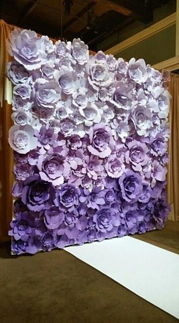 A Quinceanera image featuring lavender decorations, Quinceañera dresses, and a purple and white backdrop adorned with paper flowers