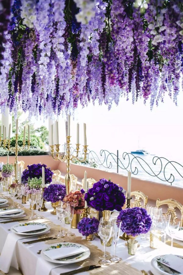 A beautiful Quinceanera table decorated with purple flowers and candles