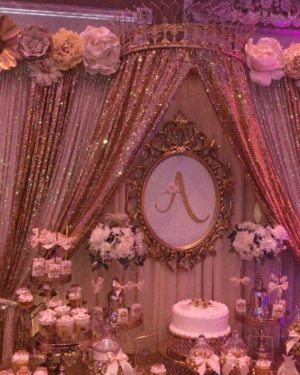 A white cake with a rose gold theme Quinceanera. On top of the cake are a bunch of purple cake pops.