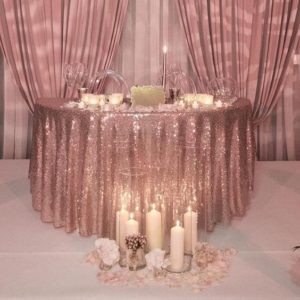 Table decorated with rose gold decorations, candles, and flowers for a Quinceanera celebration