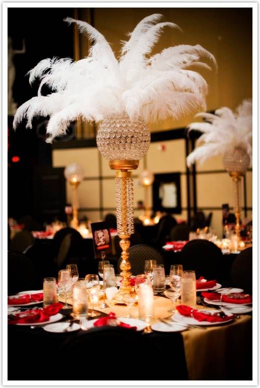 A Quinceanera image depicting a hollywood glam party theme. The image shows a table topped with a tall vase filled with white feathers.