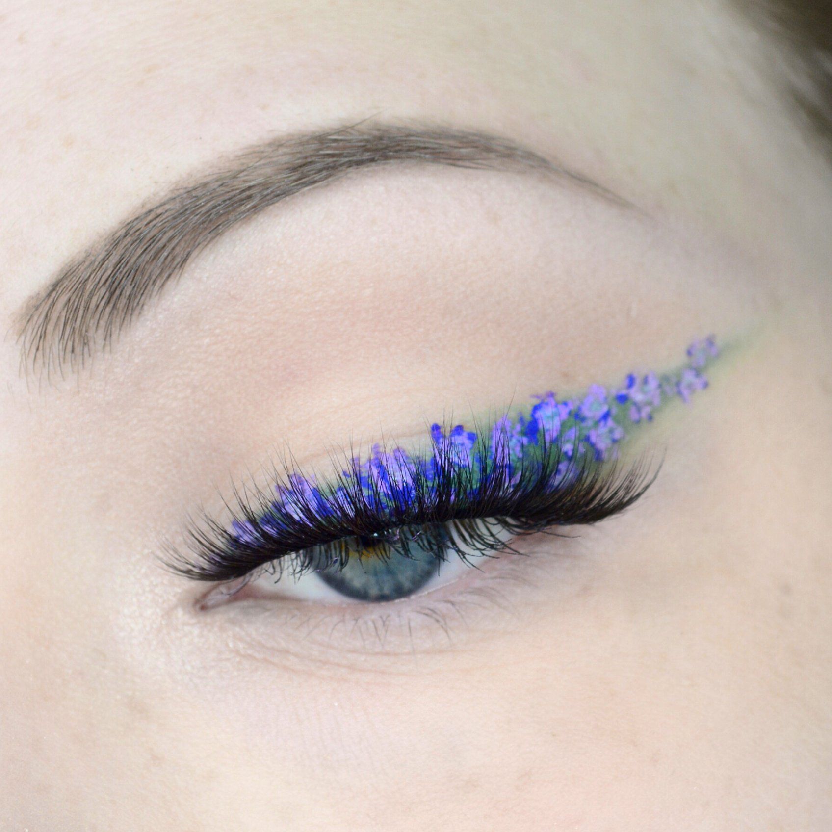 A close up of a person with long eyelashes and flowers