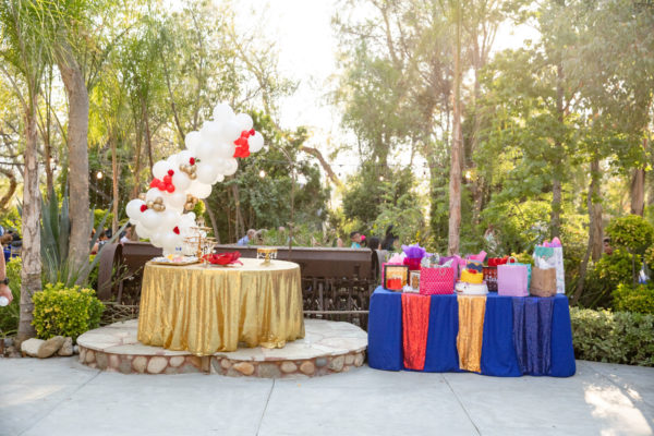 A table in a backyard with a bunch of Quinceanera presents on it.