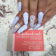 A woman's hand with blue and white nails holding a bottle of nail polish