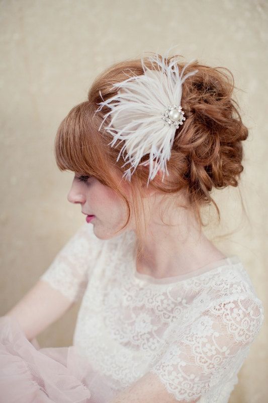 A Quinceanera woman wearing a white dress with a feathered headpiece, featuring nude eye makeup and red lips.