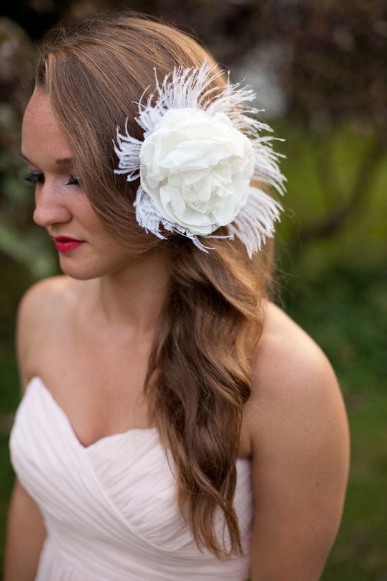 A young woman with long hair wearing a white dress and a flower in her hair, posing elegantly for her Quinceanera party