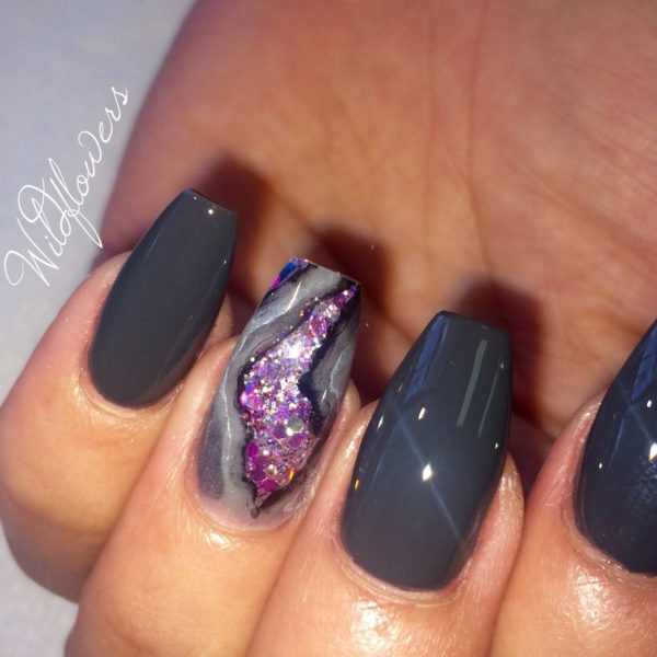 A person holding a black and purple manicure with impactful nail designs for a Quinceanera theme.