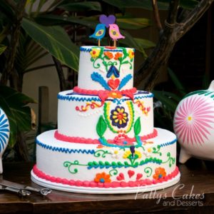 A beautiful three-tiered quinceanera cake decorated with sugar flowers and birds.