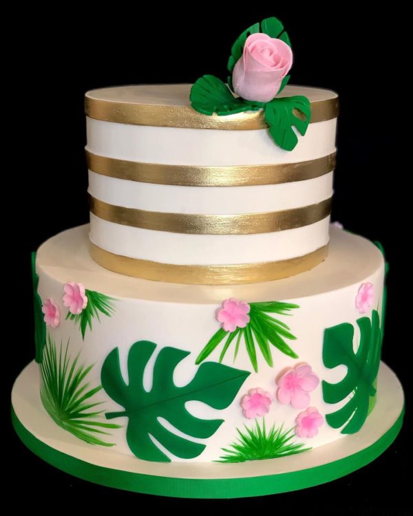 A Quinceanera cake, a three-tiered cake adorned with pink flowers and green leaves.