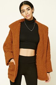 A woman wearing a cardigan coat, brown jacket, and black pants at a Quinceanera celebration.