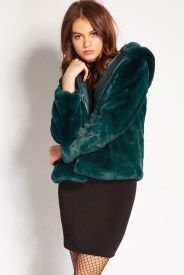 A woman wearing fur clothing, a green jacket, and a black skirt at a Quinceanera event.