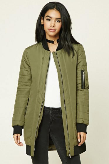 A fashionable Quinceanera model wearing a green bomber jacket and black jeans.