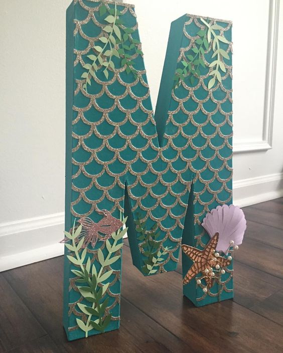 Quinceanera image of a wooden letter m decorated with leaves in a mermaid theme