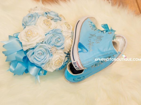 A beautiful Quinceanera decoration with turquoise artificial plants, a bouquet of flowers, and a pair of blue shoes.