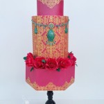 A Quinceanera themed three tiered cake with pink icing and topped with red roses.