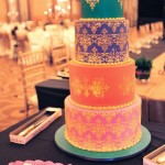 A multicolored Quinceanera cake sitting on top of a table with cake decorating