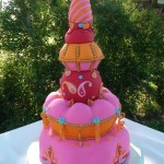 A three-tiered Sugar cake decorated with pink and orange decorations for a Quinceañera celebration.