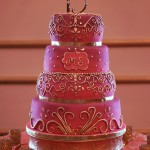 A three-tiered Quinceanera cake on a table with cupcakes in an Arabian theme