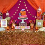 A Quinceanera party with an Arabian style theme. The image shows a table topped with a cake and lots of candy.