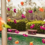 A Quinceanera floral decoration featuring an Indian-inspired design, with a bunch of flowers hanging from a pole near a pool.