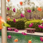A Quinceanera floral decoration featuring an Indian-inspired design, with a bunch of flowers hanging from a pole near a pool.