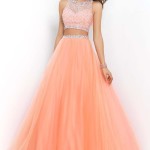 A woman in a salmon Lehenga standing in front of a white wall at a Quinceanera celebration
