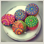 Quinceanera themed image featuring a white plate topped with cupcakes covered in colorful icing, alongside cookies and crackers