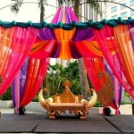 A Quinceanera stage decorated with colorful drapes and flowers in a Bollywood-inspired theme