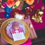 A table set for a Quinceanera celebration with a pink table cloth and a gold plate, adorned with cut flowers.