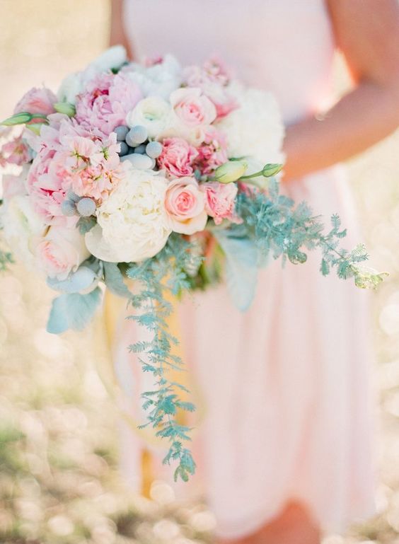 A woman holding a pastel color Quinceanera bouquet of pink and white flowers