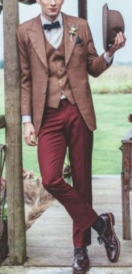 A man wearing a gentleman suit and hat standing on a porch at a Quinceanera event