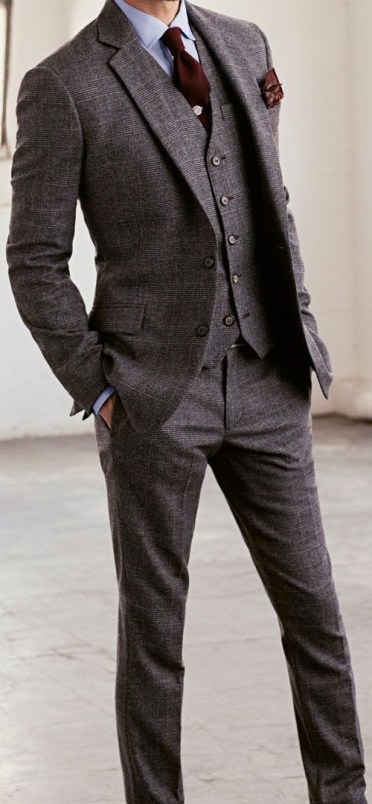 A man in a grey suit and tie posing for a picture at a Quinceanera