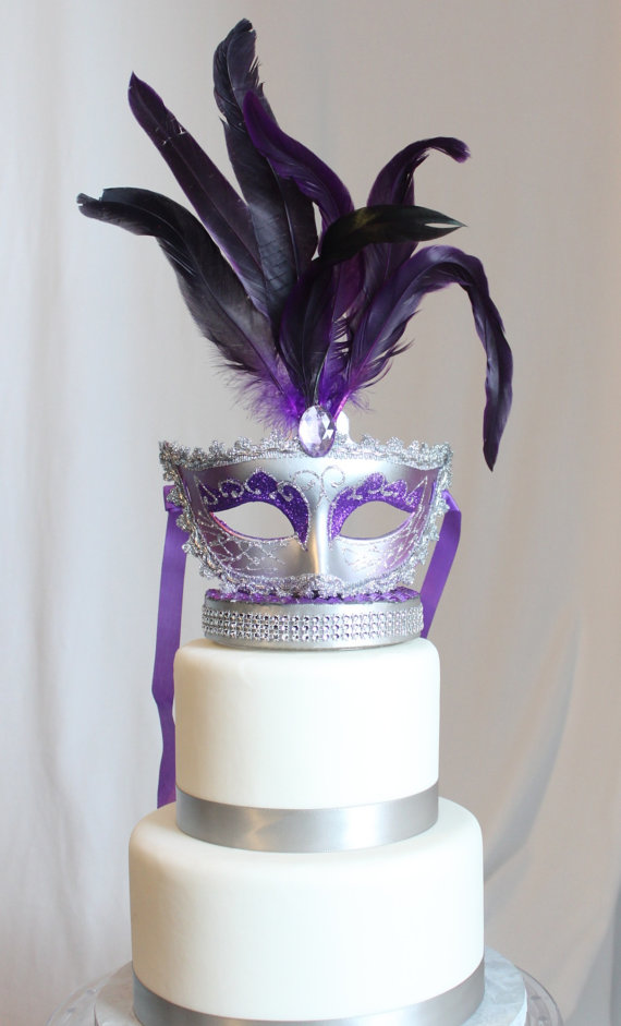 Quinceanera cake, a white cake with purple feathers and a mask on top
