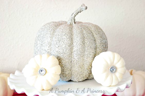 A Quinceanera cake featuring a white glitter pumpkin, a silver pumpkin, and two white pumpkins