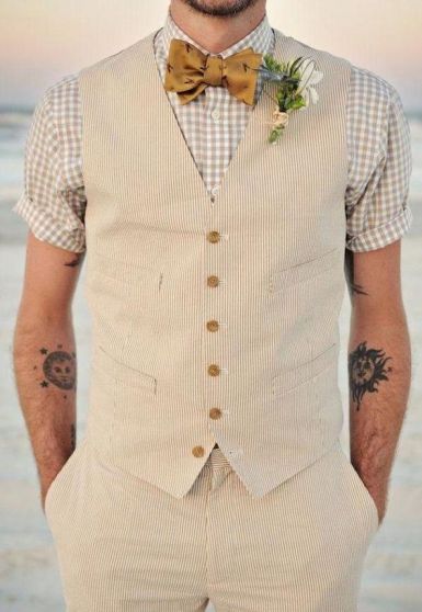 A man in a short sleeve wedding suit, wearing a vest and bow tie, standing on the beach during a Quinceanera celebration