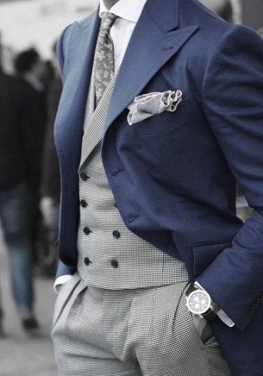 A man wearing a blue dogtooth suit and tie, standing on the street