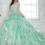 A woman in a green two-piece Quinceanera dress standing in front of a window