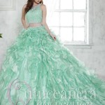 A woman in a green two-piece Quinceanera dress standing in front of a window