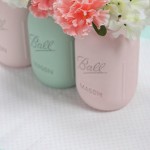 Three mason jars with Quinceanera flowers on a table