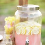 A light pink and yellow Quinceanera theme with a pink beverage dispenser sitting on a table