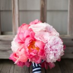 Quinceanera flower bouquet, featuring a pink peony bouquet with navy blue ribbon on a wooden floor