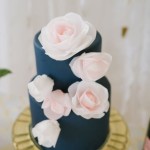 A navy blue and pastel pink Quinceanera Invitation with a close-up view of a cake adorned with flowers.